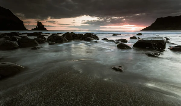 Arena negra y rocas en la orilla del mar — Foto de Stock