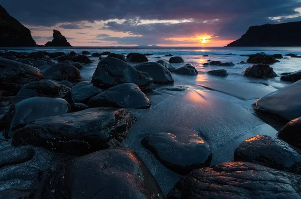 Arena negra y rocas en la orilla del mar — Foto de Stock