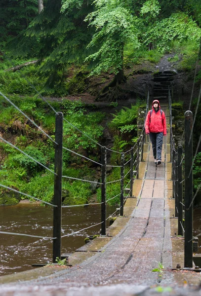 Hiker crossing suspension bridge — Stock Photo, Image