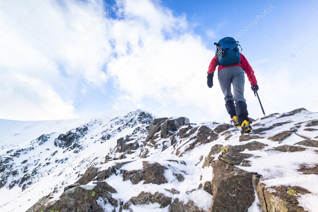 A climber ascending a snow covered ridge 