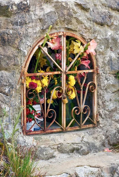 Fleurs au monument de fer dans le mur de pierre — Photo
