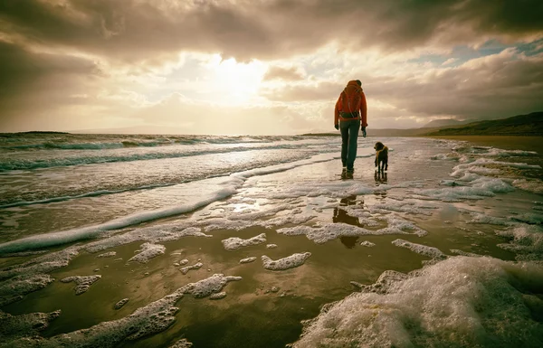 Una mujer en la playa con su perro — Foto de Stock