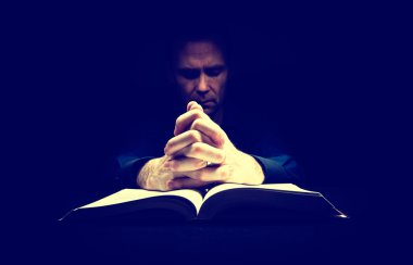 İncil üzerine adam dua ediyor