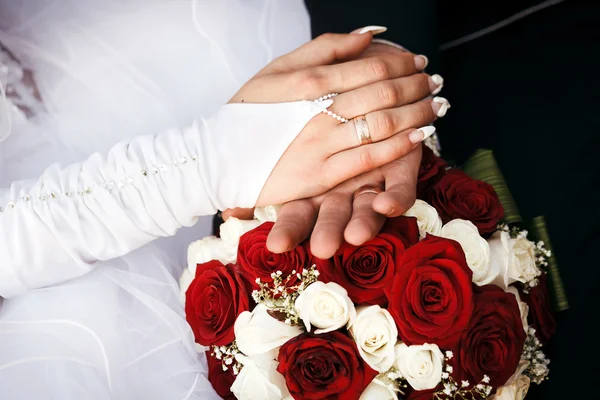 Mani di sposo e sposa con fedi nuziali, bouquet da sposa . — Foto Stock
