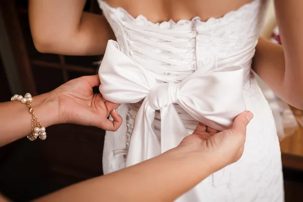 Demoiselle d'honneur aide à mariée à mettre sur la robe de mariée . — Photo