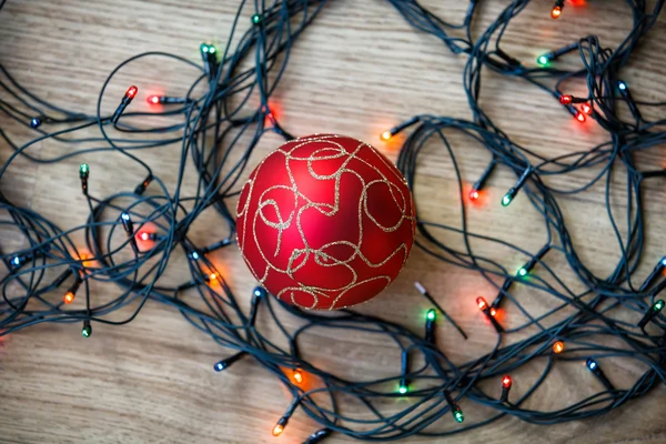 Luz guirlanda e bola de Natal no fundo de madeira . — Fotografia de Stock