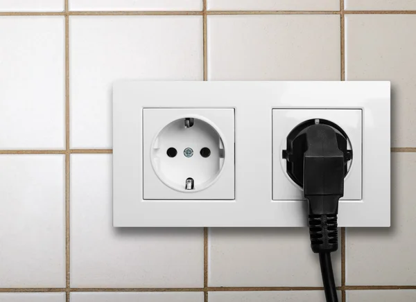 Svart kabel inkopplad en vit eluttag — Stockfoto