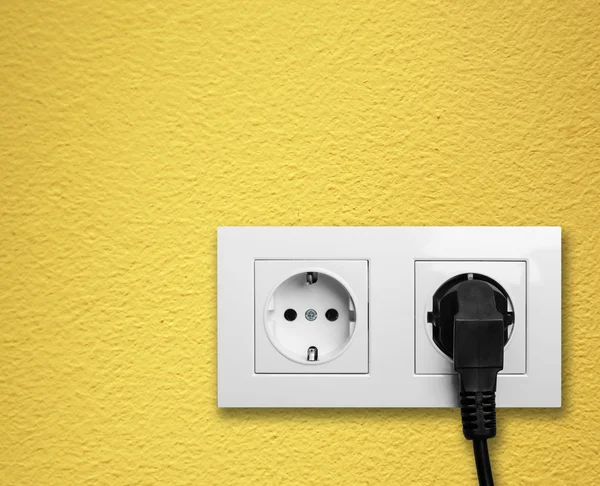Чорний кабель підключений до білого електричного розетки — стокове фото