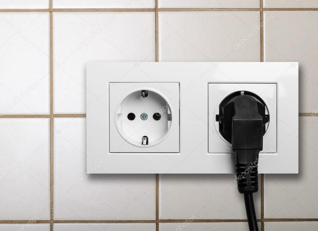 Black cable plugged in a white electric outlet