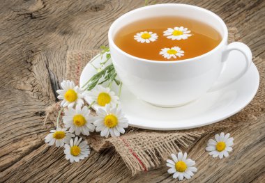 Fincan çay ve chamomiles ahşap arka plan üzerinde