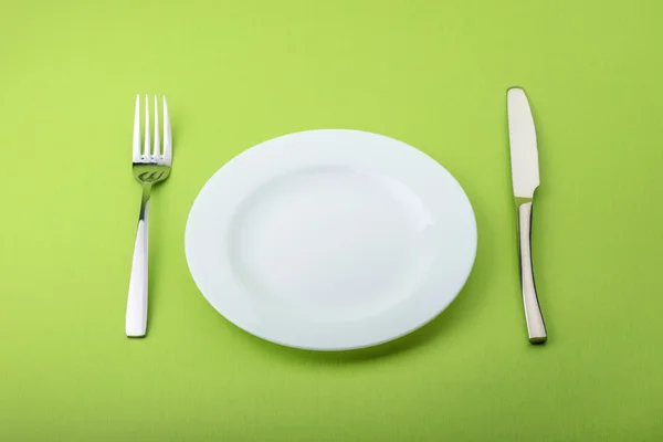 Assiette, fourchette et couteau vides sur fond vert — Photo