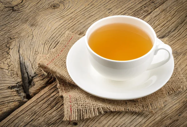 Cup of tea and chamomiles on wooden background — Stock Photo, Image