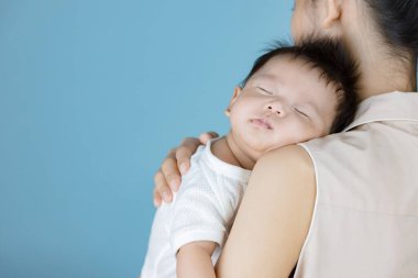 Küçük bebek annesinin göğsünde uyuyor.