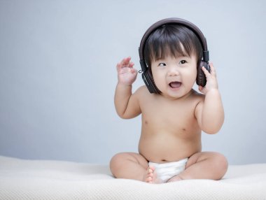 Kulaklığın başında oturan ve müzik dinleyen tatlı bir erkek bebek.