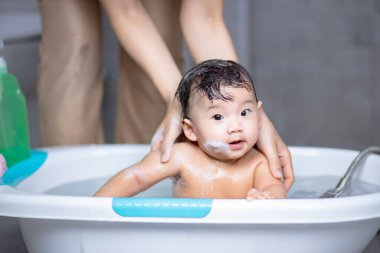 Köpükle banyo yapan sevimli bebek.