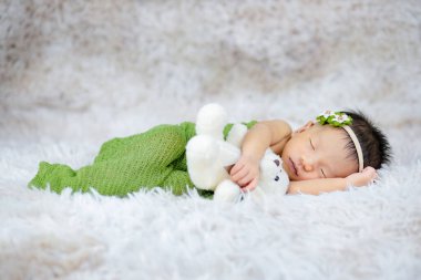 Küçük bebek uzanmış oyuncak ayıya sarılıyor