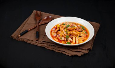 Siyah arka planda baharatlı sosis salatası.