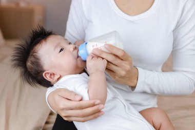 Anne bebeği süt şişesiyle besliyor.