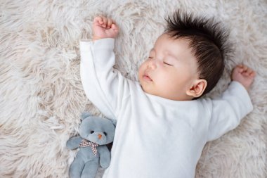Küçük bebek oyuncak ayıyla uzanıyor.
