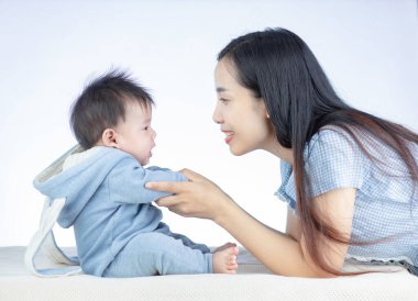 Güzel genç anne mavi tavşan kostümlü küçük bebeğine bakıyor.