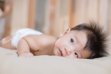 Neşeli küçük bebek yatakta yatıyor.