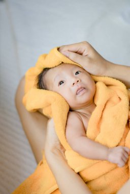 Anne, bebeği turuncu havluyla ovala.