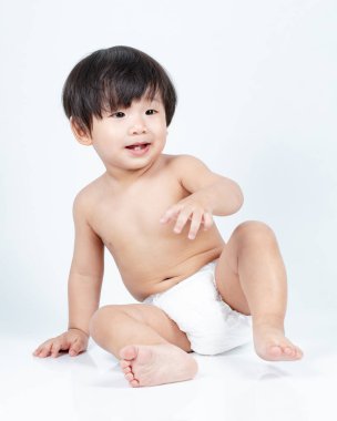 Yerde oturan çocuk, beyaz arka planda izole edilmiş. 