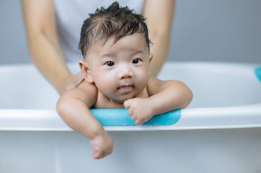 Anne ellerinde yıkanan küçük bebek.