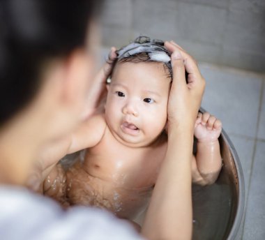 Anne tarafından havuzda yıkanan yeni doğmuş bir bebek.