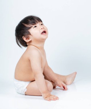 Yerde oturan çocuk, beyaz arka planda izole edilmiş. 