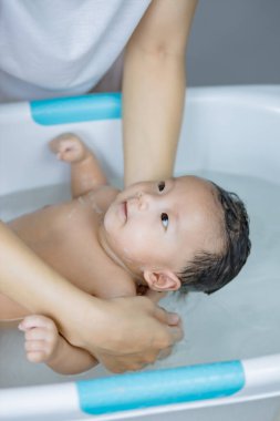 Anne ellerinde yıkanan küçük bebek.