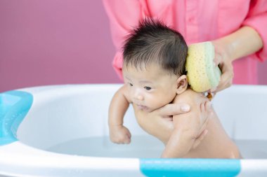 Yenidoğan, annesinin pembe arka planında havuzda banyo yapıyor.