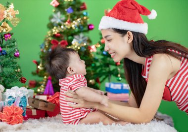 Mutlu Noeller ve mutlu tatiller! Neşeli anne tatlı küçük bebeğine bakıyor..