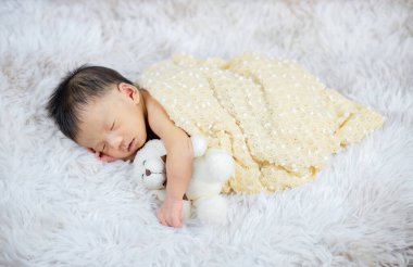 Küçük bebek uzanıyor ve bir oyuncak ayı.