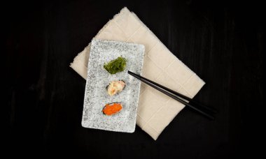 Siyah arkaplanda tabak içinde suşi seti.