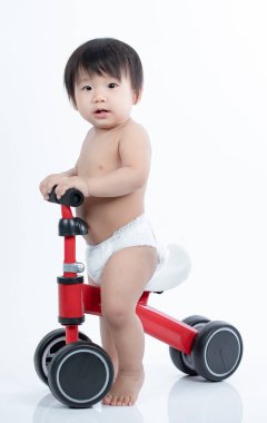 Koşucudaki şirin bebek dengeyi sağlamayı öğreniyor. Bisiklet beyaz arka planda izole edilmiş.