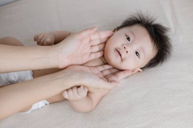 Anne yatakta masaj yapan bir bebek.