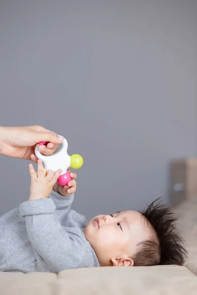 赤ん坊見ますで手保持カラフルなおもちゃ上赤ちゃん — ストック写真