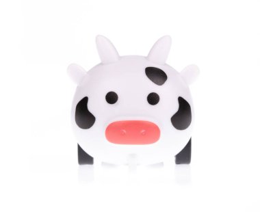 Oyuncak inek kendini beyaz bir arka planda yalnız bulur..