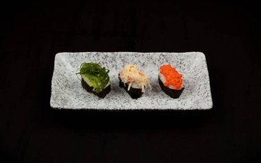 Siyah arkaplanda tabak içinde suşi seti.