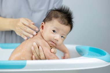 Anne, bebeğini banyoda yıkıyor.      