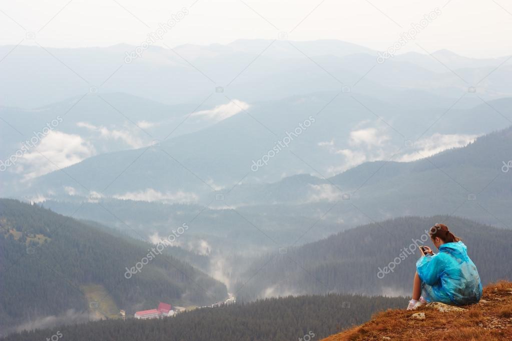 Girl with mobile phone on top of mountain