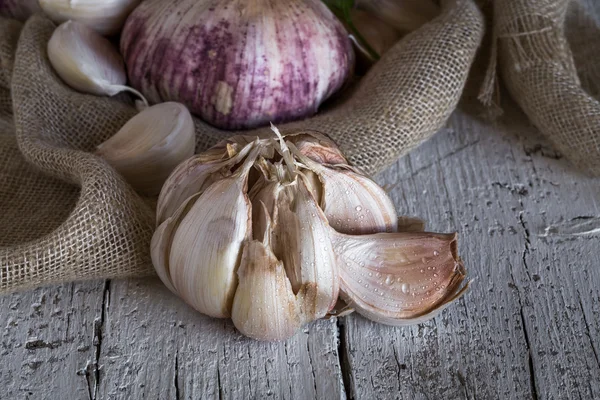 Lila garlics på en servett på ett rustikt träbord — Stockfoto