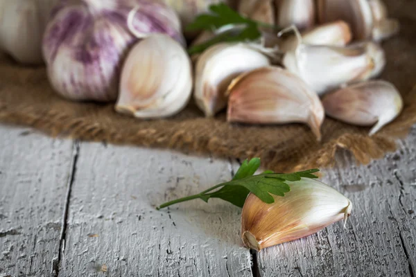 Lila garlics på en servett på ett rustikt träbord — Stockfoto