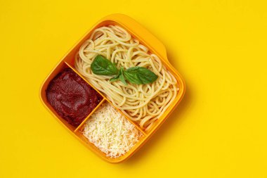 Plastik kutulardaki sağlıklı yiyecekler, çalışma masasında ev yapımı spagetti, domates, peynir ve fesleğen ile birlikte yemeye hazır. İtalyan yemeği. Götürmek için.