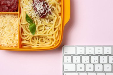 Plastik kutulardaki sağlıklı yiyecekler, çalışma masasında ev yapımı spagetti, domates, peynir ve fesleğen ile birlikte yemeye hazır. İtalyan yemeği. Götürmek için.