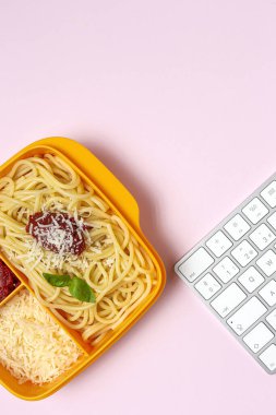Plastik kutulardaki sağlıklı yiyecekler, çalışma masasında ev yapımı spagetti, domates, peynir ve fesleğen ile birlikte yemeye hazır. İtalyan yemeği. Götürmek için.