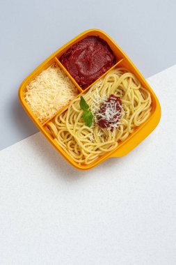 Plastik kutulardaki sağlıklı yiyecekler, çalışma masasında ev yapımı spagetti, domates, peynir ve fesleğen ile birlikte yemeye hazır. İtalyan yemeği. Götürmek için.