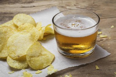 Evde patates cipsi, bira, kraker, yeşil ve siyah zeytinli çerezler var.