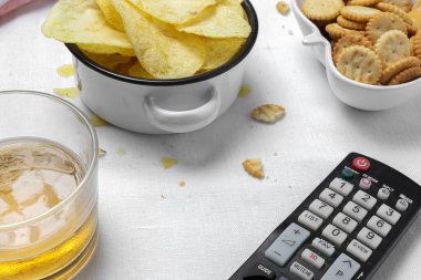 Evde çerez çeşitleri patates cipsi, bira, kraker, yeşil ve siyah zeytinli masa örtüsü.